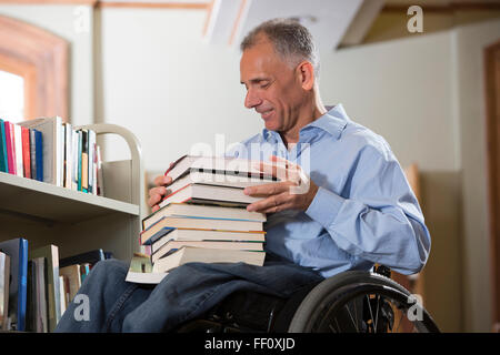 Caucasian man choisir book in library Banque D'Images