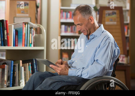 Caucasian man using digital tablet in library Banque D'Images