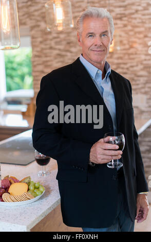 Young man drinking wine in kitchen Banque D'Images