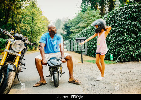 Père assis sur moto miniature près de fille Banque D'Images