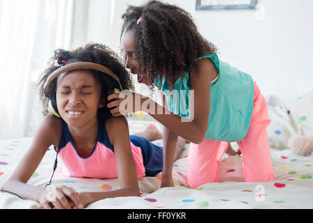 Mixed Race girl peine sister on bed Banque D'Images