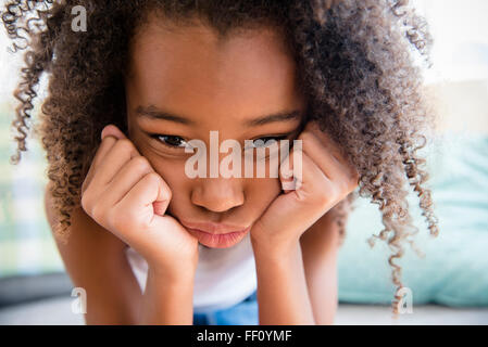 Moody mixed race girl resting chin in hand Banque D'Images