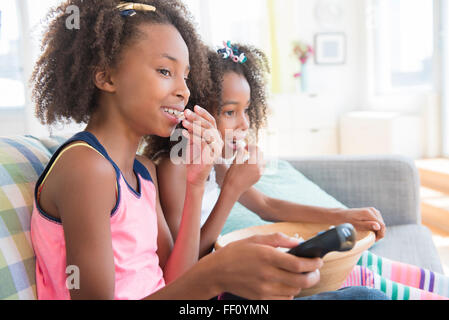 Mixed Race girl watching television on sofa Banque D'Images