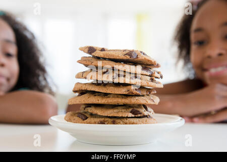 Mixed Race girl admiring pile de cookies Banque D'Images