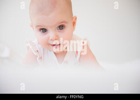 Caucasian baby girl crawling on bed Banque D'Images