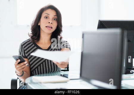 Mixed Race businesswoman working at desk Banque D'Images