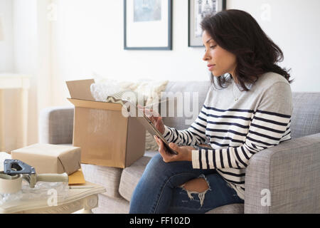 Mixed Race business owner using digital tablet on sofa Banque D'Images