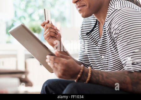 Mixed Race man shopping online with digital tablet Banque D'Images