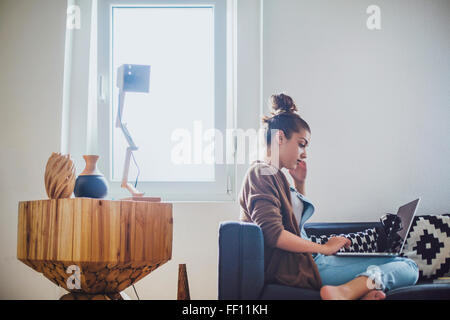 Caucasian woman using laptop on sofa Banque D'Images