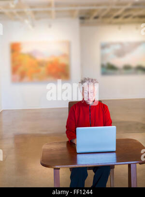 Plus mixed race woman using laptop in art gallery Banque D'Images