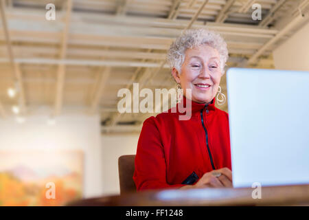 Plus mixed race woman using laptop in art gallery Banque D'Images