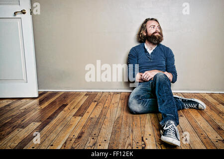 Caucasian man sitting on floor Banque D'Images