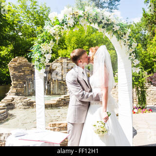 Premier baiser des nouveaux mariés en vertu de l'arche de mariage Banque D'Images