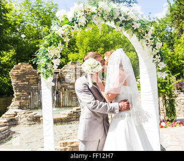 Premier baiser des nouveaux mariés en vertu de l'arche de mariage Banque D'Images