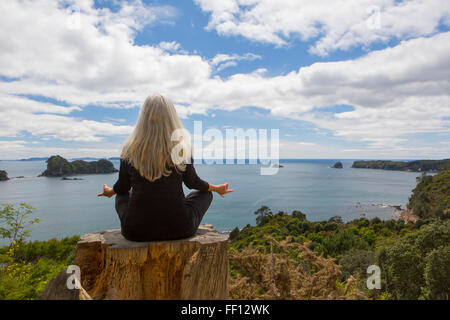 Older Caucasian woman meditating on cliff près de ocean Banque D'Images