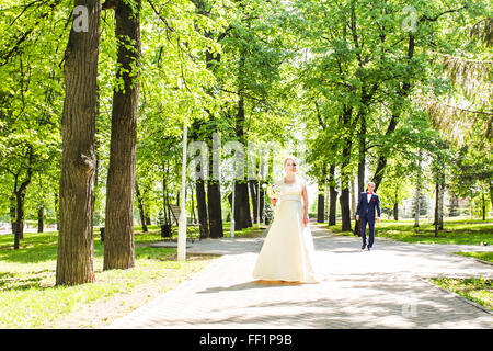 Tenue de mariage en couple avec un bouquet de fleurs et de verdure est dans les mains sur la toile de fond du jardin, de la mariée et le marié Banque D'Images