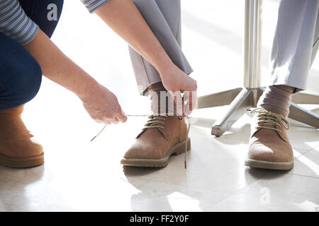 Sa fille adulte aidant les attacher ses lacets Banque D'Images