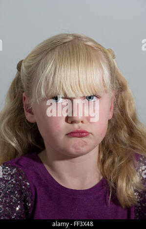 Portrait d'une jeune fille blonde avec des grappes sur un fond blanc. Banque D'Images