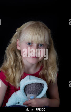 Portrait d'une jeune fille blonde avec des grappes sur un fond blanc. Banque D'Images
