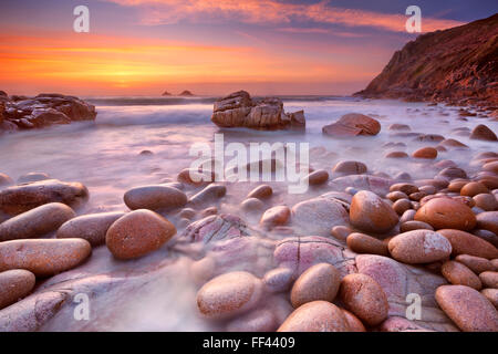 La belle plage de Porth Nanven rocheuses à Cornwall, Angleterre au coucher du soleil. Banque D'Images