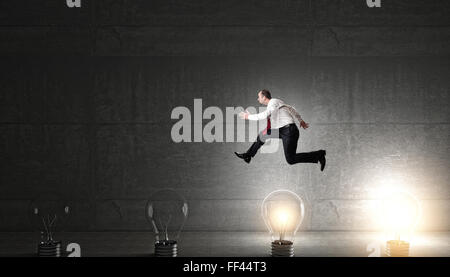 L'homme saute sur l'ampoule 3d concept d'idée Banque D'Images