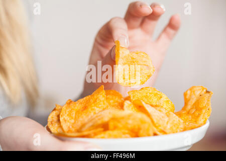 Woman eating potato chips Banque D'Images