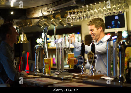 Un barman pulling a pint dans un pub anglais traditionnel Banque D'Images