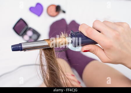 Vue de dessus d'un redressage fille ses cheveux alors qu'il était assis dans le lit Banque D'Images