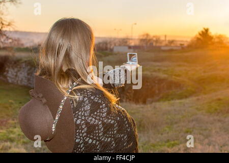 Girl pointing sa boussole au coucher du soleil Banque D'Images