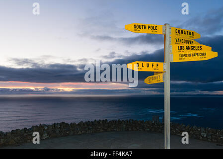 Signer avec les distances en km et nm de Cape Reinga, Nouvelle-Zélande au crépuscule Banque D'Images