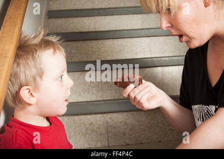 Portrait de famille de fils nourrir sa mère barre de chocolat Banque D'Images