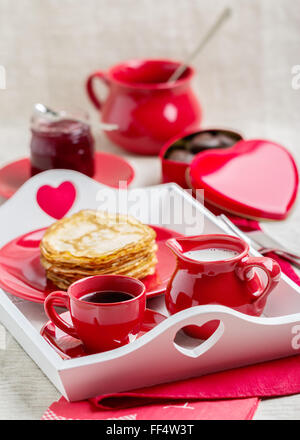 Le petit-déjeuner. Crêpes et café au lait sur un plateau pour la Saint-Valentin. Focus sélectif. Banque D'Images