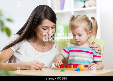 Petite fille est la résolution de casse-tête. Mère regardant à ses actions Banque D'Images