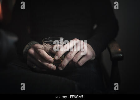 A man's hands holding un verre de whisky. Banque D'Images