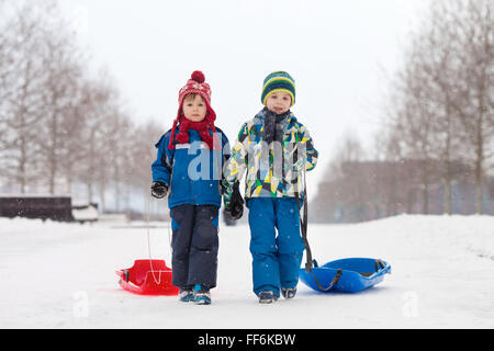 Deux enfants, frères, glissant le garçon avec Bob dans la neige, hiver, concept de bonheur Banque D'Images