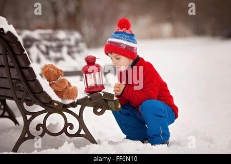 Adorable petit garçon caucasien enfant, jouet moelleux, tenant et serrant, dans le parc, sur la journée d'hiver ensoleillée Banque D'Images