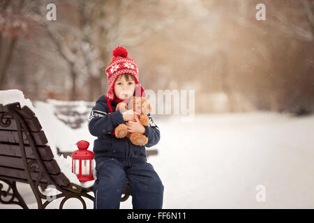 Adorable petit garçon caucasien avec ours et lanterne rouge, jouant dans le parc d'hiver, jour de neige Banque D'Images