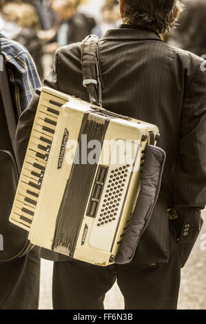 Homme portant un costume porte un accordéon blanc sur son dos Banque D'Images