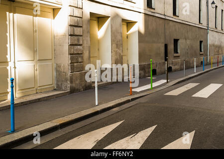 Posts peintes en différentes couleurs sur une rue déserte Banque D'Images