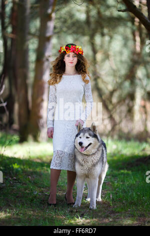 Portrait d'une belle jeune fille avec un chien husky dans une forêt au printemps Banque D'Images