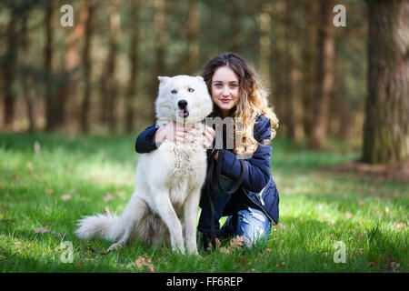 Happy young girl embracing chien husky dans une forêt au printemps Banque D'Images