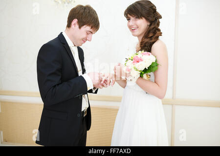 Les mariés l'un à l'autre portant des anneaux de mariage Banque D'Images