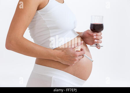 Près d'une femme enceinte irresponsable avec la cigarette et le vin rouge Banque D'Images