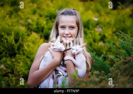 Portrait of a smiling young girl avec les chats sphinx dans une forêt verte Banque D'Images