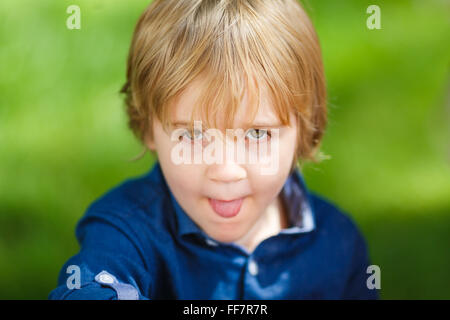 Portrait d'un petit garçon mignon montrant langue sur le fond vert Banque D'Images