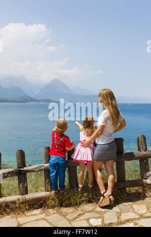 Mère de deux enfants près de clôture en bois vu sur le seascape Banque D'Images