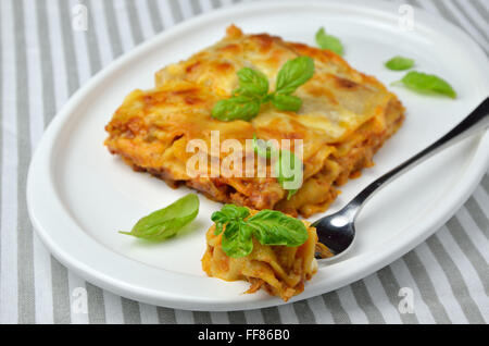 Lasagne aux feuilles de basilic servi sur assiette, avec la fourchette Banque D'Images