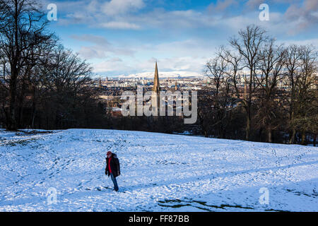 Un homme marche dans la neige, Queens Park, Glasgow. Le parc est connu pour sa vue sur le côté sud de Glasgow, avec un couvert de neige Campsie Fells en arrière-plan. Banque D'Images