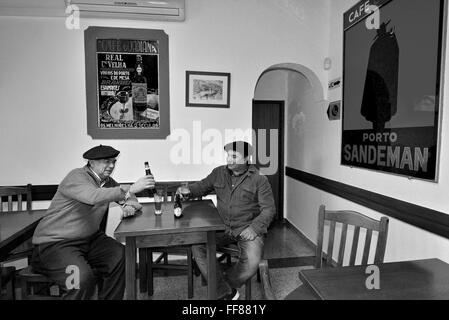Le Portugal, l'Alentejo : deux hommes autochtones ayant une bière et un chat dans le café traditionnel Guadiana dans Mértola (bw) Banque D'Images