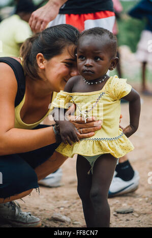 Mali, Afrique - Young caucasian woman bénévoles ayant du plaisir à jouer et danser avec un bébé femelle noire près de Bamako Banque D'Images